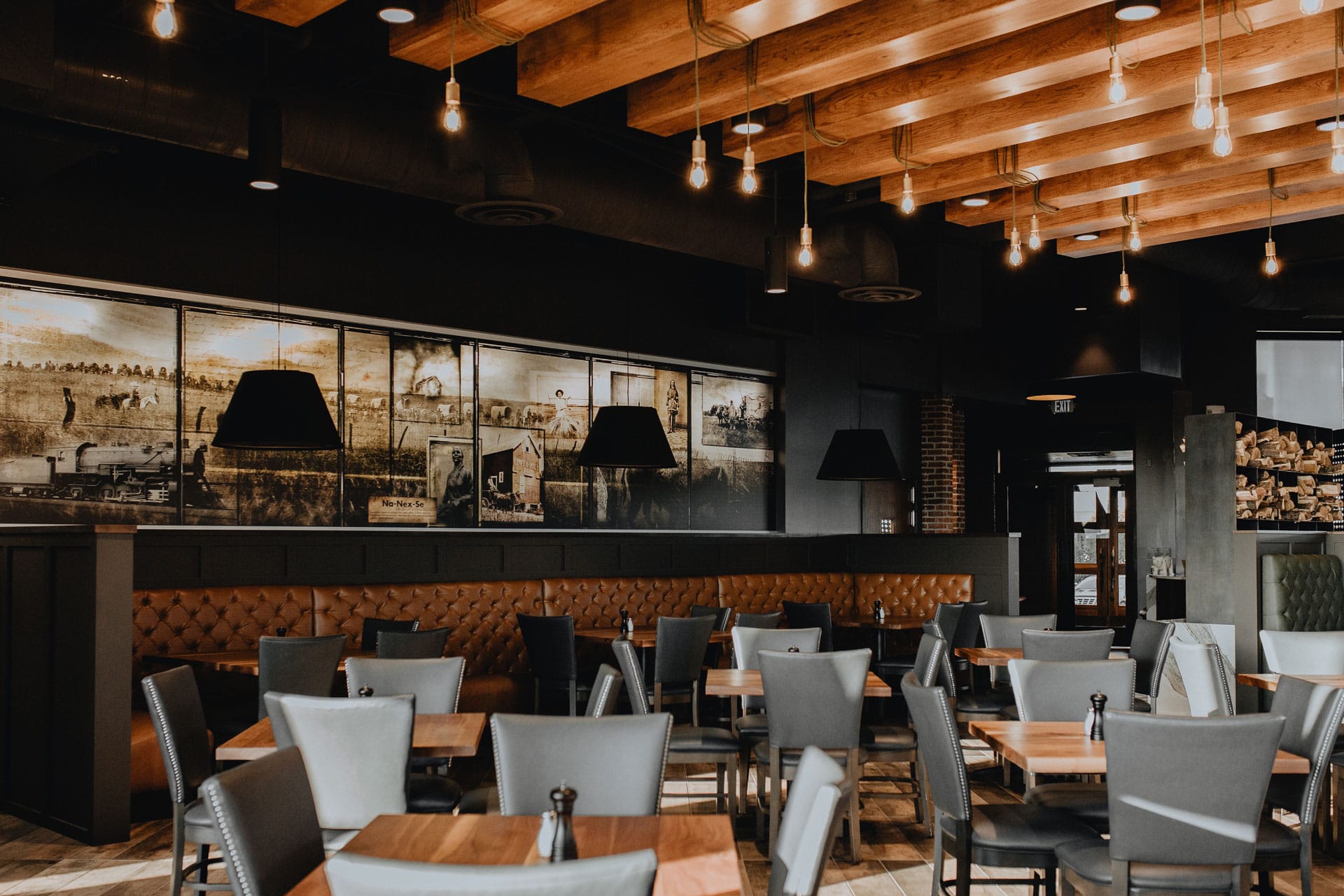 Warm dining room with exposed wood ceiling beams and atmospheric pendant lighting.
